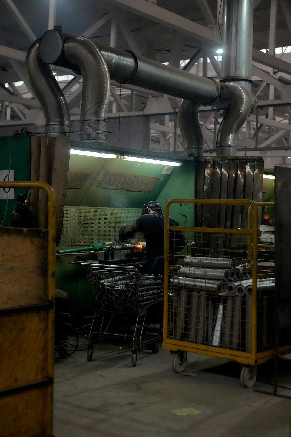 Worker in a hard hat grinds metal in a factory.